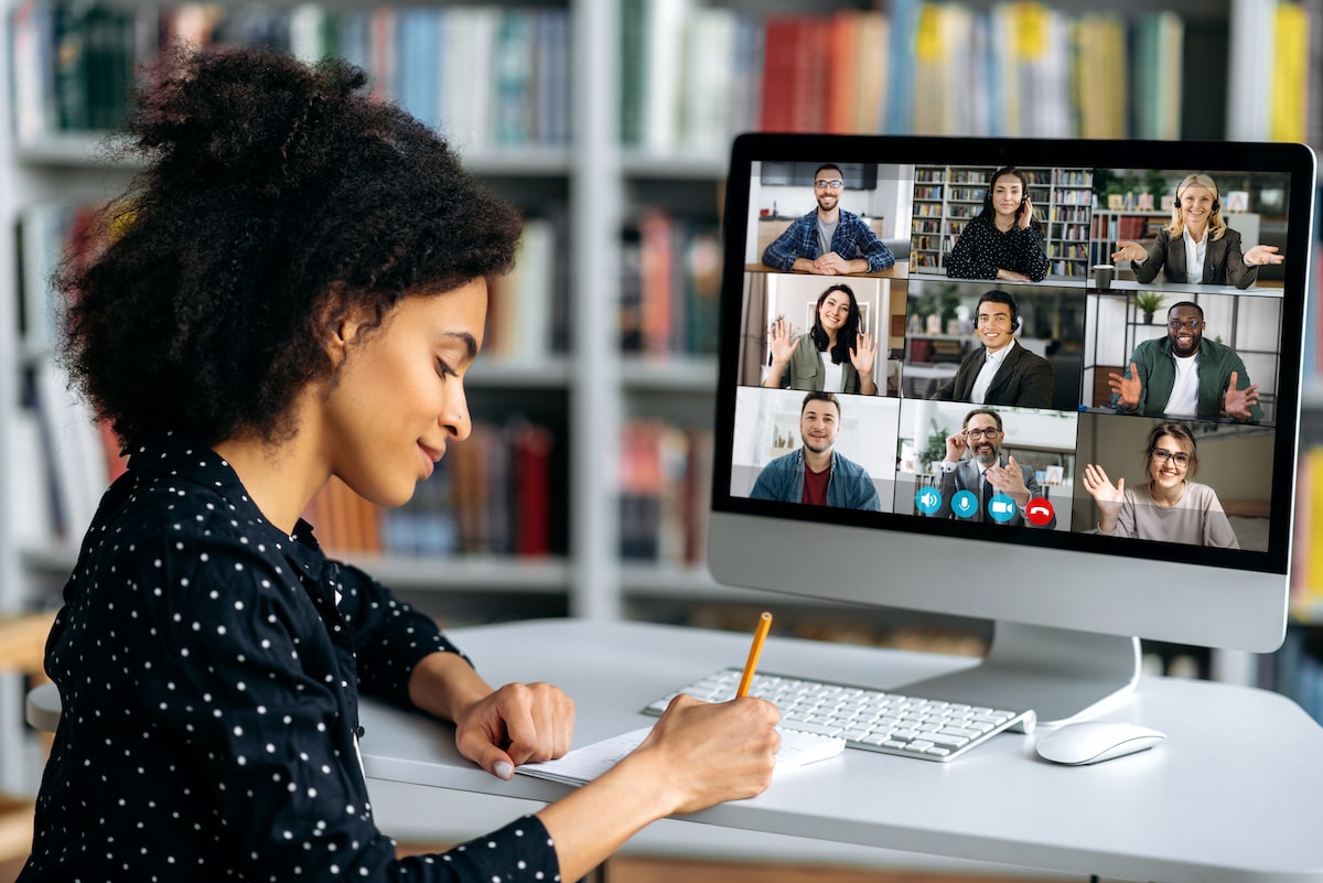 A woman sits learning how to code with fellow students in a video call on her computer.