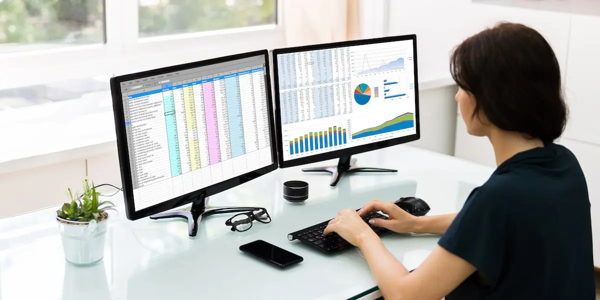 Data analyst uses two monitors to work on datasets and visualizations