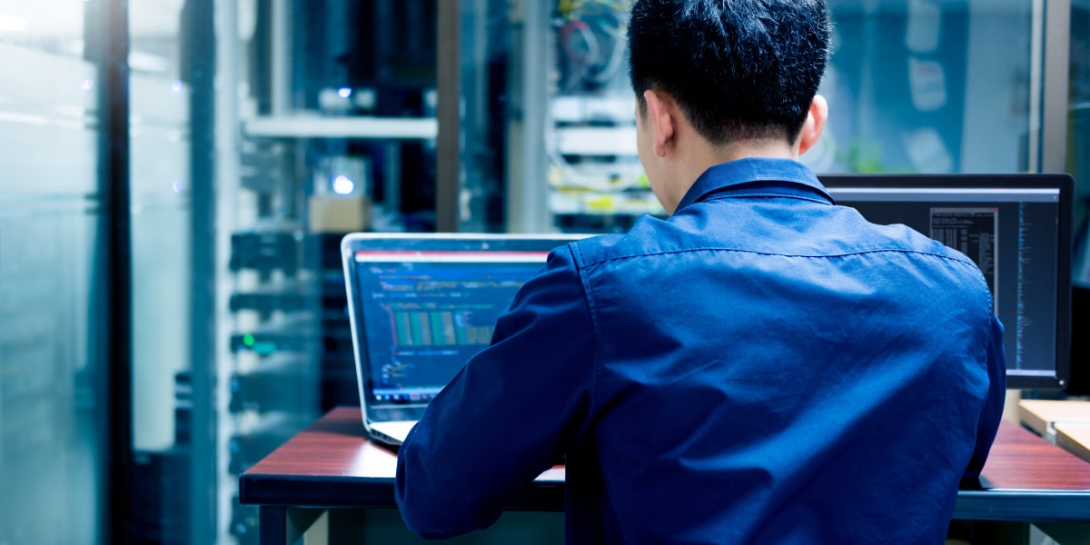 Big data engineer working on a laptop in a server room