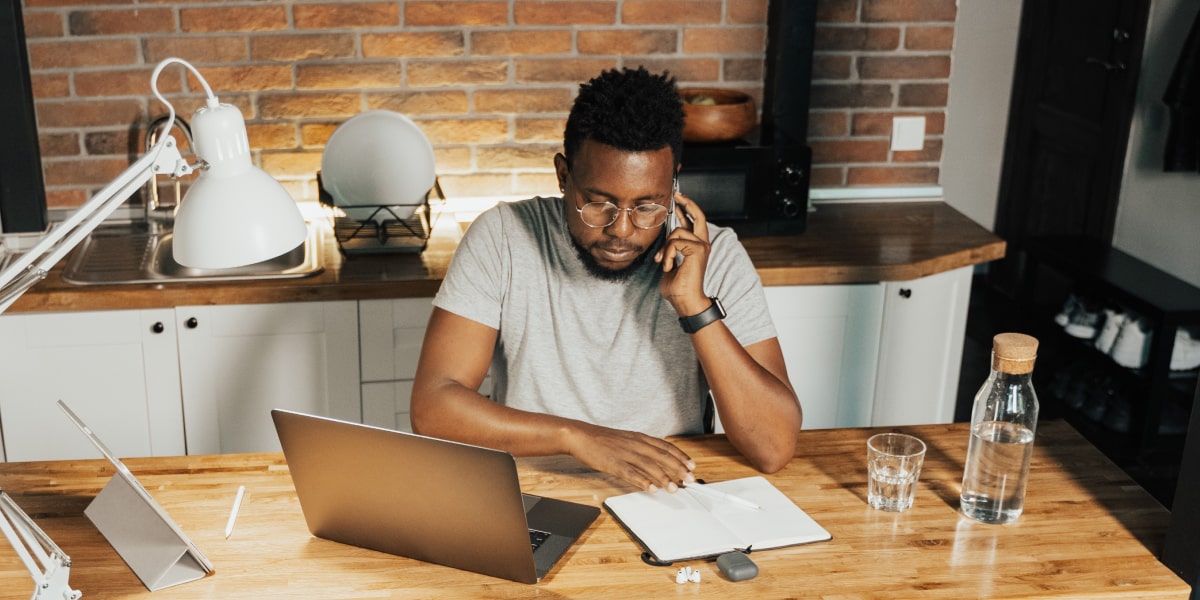 A UX designer sitting at a desk looking at papers and talking on the phone