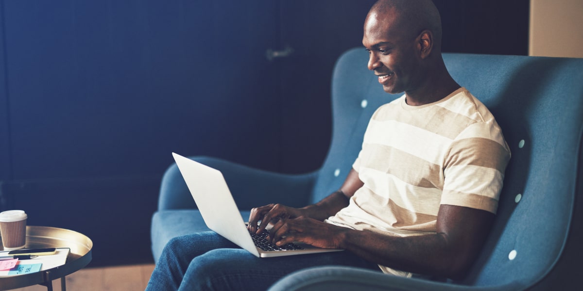 A UI design student in side profile, sitting in an armchair looking at a laptop screen