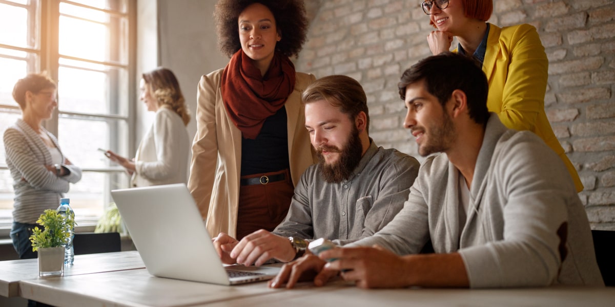 A group of designers gathered around a laptop