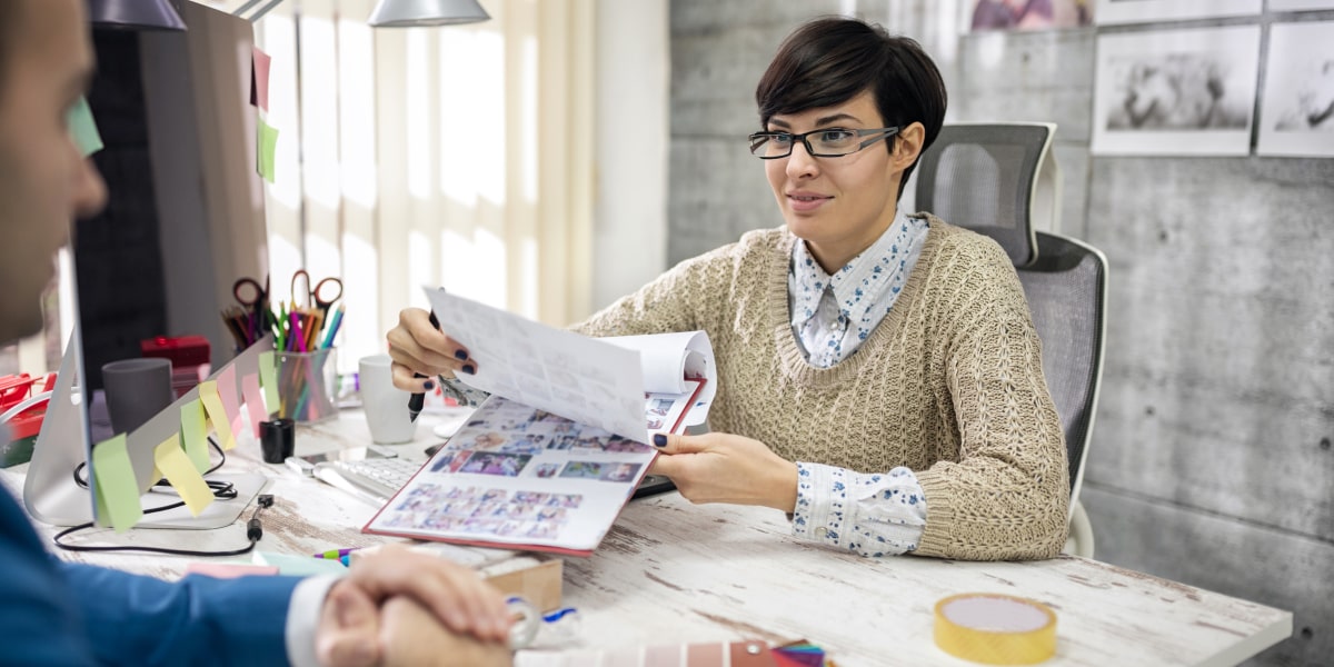 A designer showing some storyboard sketches to their colleague in an office