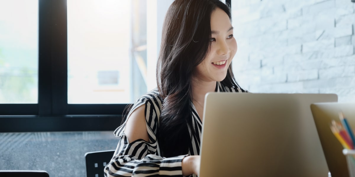 A content marketer sitting at a desk, typing on a laptop