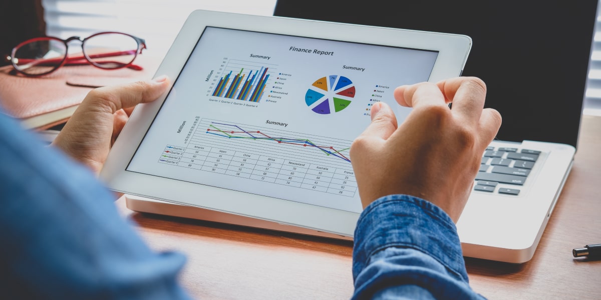 A digital marketing analyst holding an iPad, looking at graphs