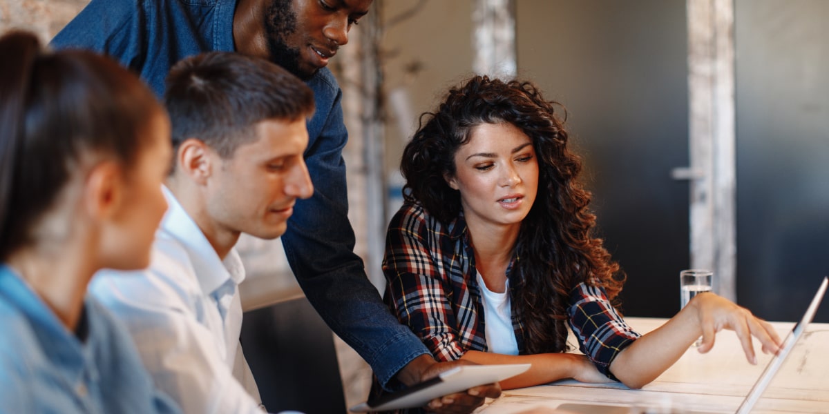 A team of digital marketers sitting at a desk, gathered around a computer screen