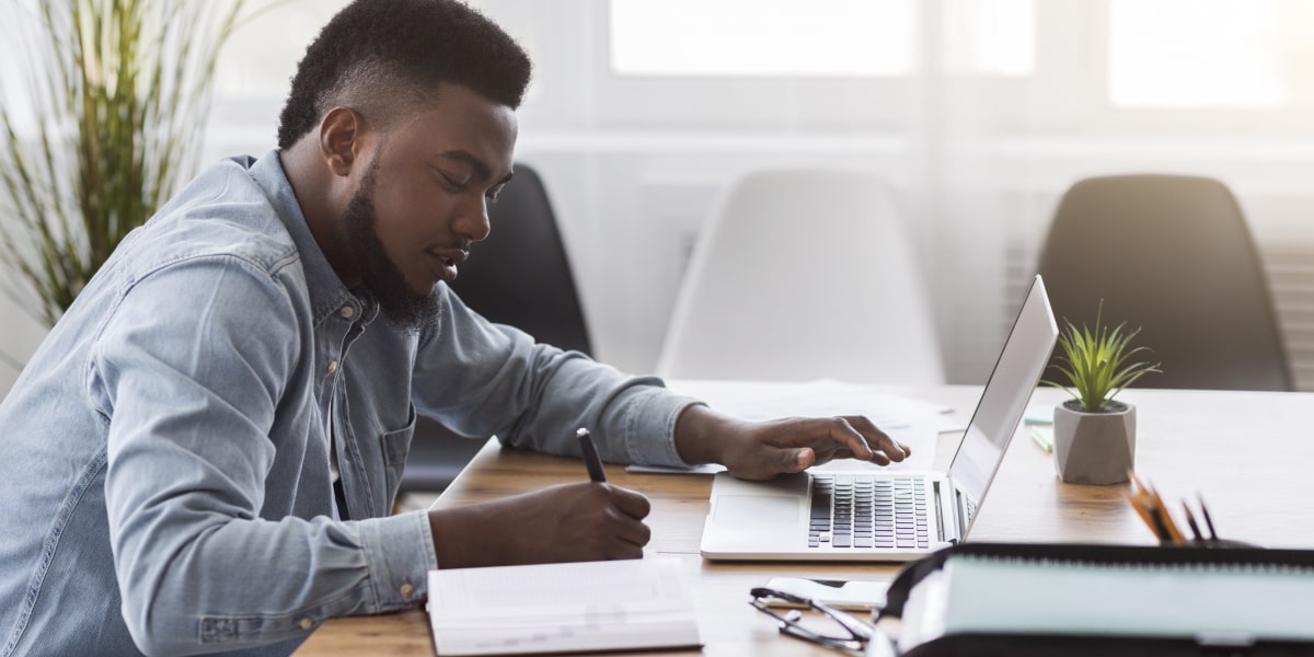 An aspiring social media manager sitting at a desk in side profile with a laptop, applying for social media jobs