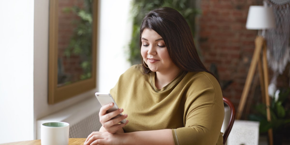 A social media specialist sitting in a cafe, looking at a phone