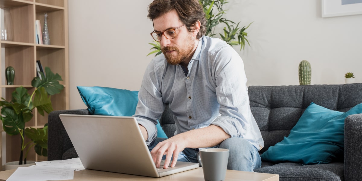 A social media specialist working from home, sitting on a sofa with a laptop