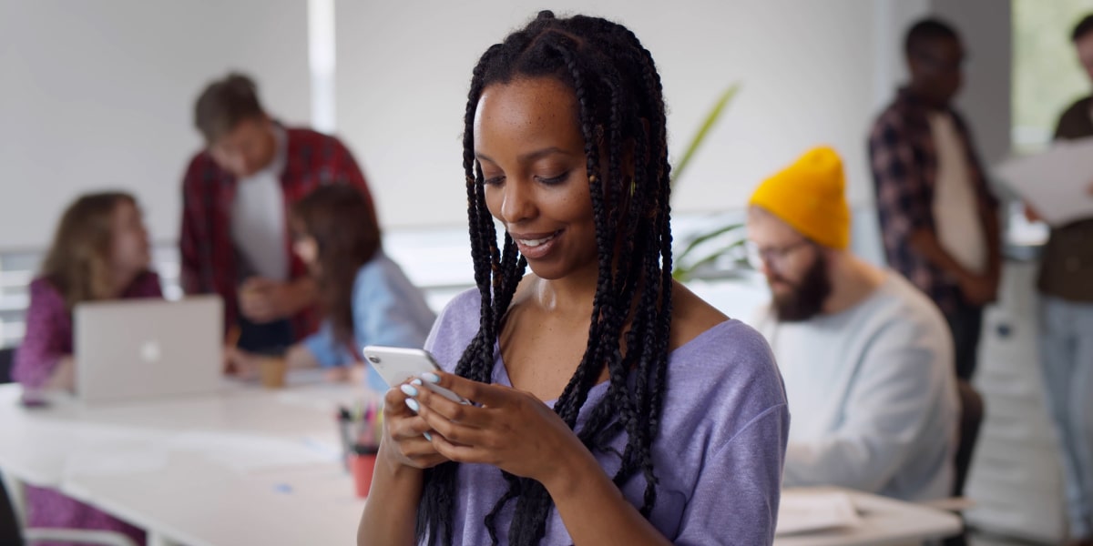 A social media marketing specialist holding a phone, posting on social media