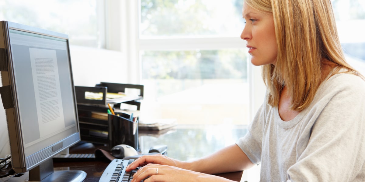 A marketing professional in side profile, sitting at a desk, typing on a computer