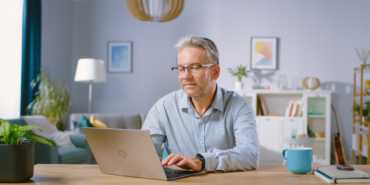 A social media specialist working from home, sitting at a desk, using a laptop