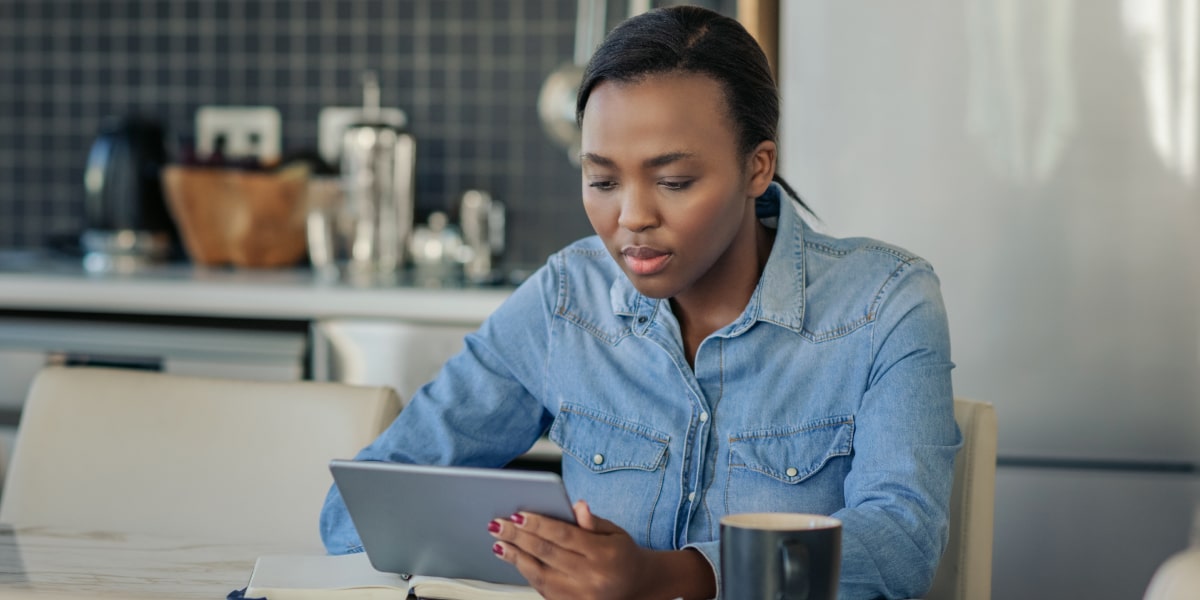 An aspiring marketer sitting at a kitchen table, holding an iPad, researching the average digital marketing specialist salary