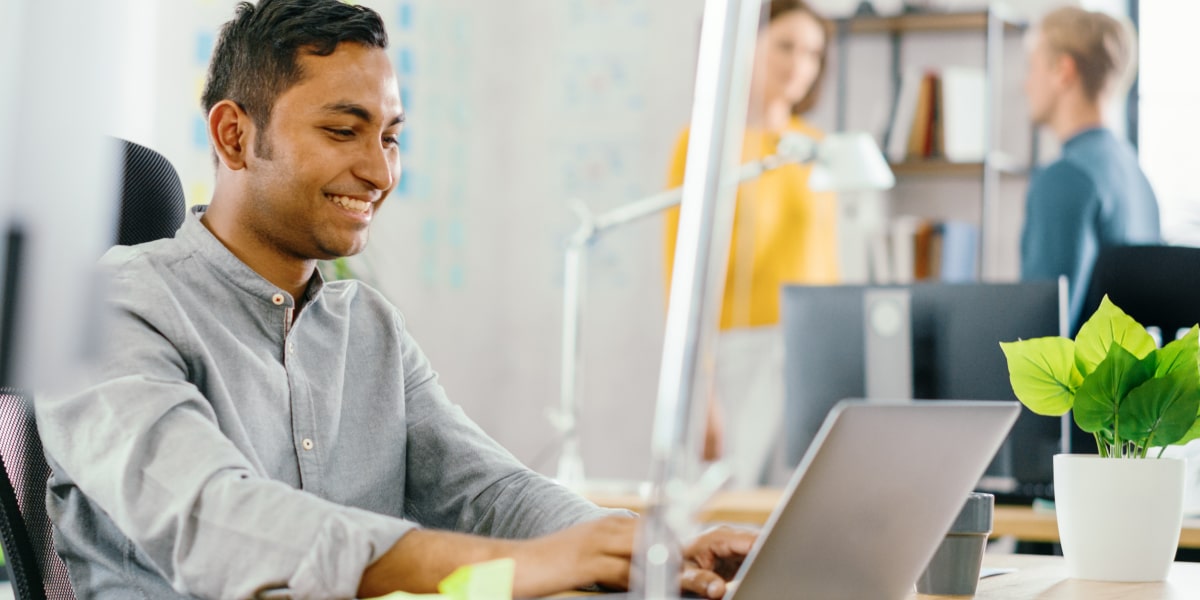 A digital marketing specialist in side profile, sitting at a desk, working on a computer