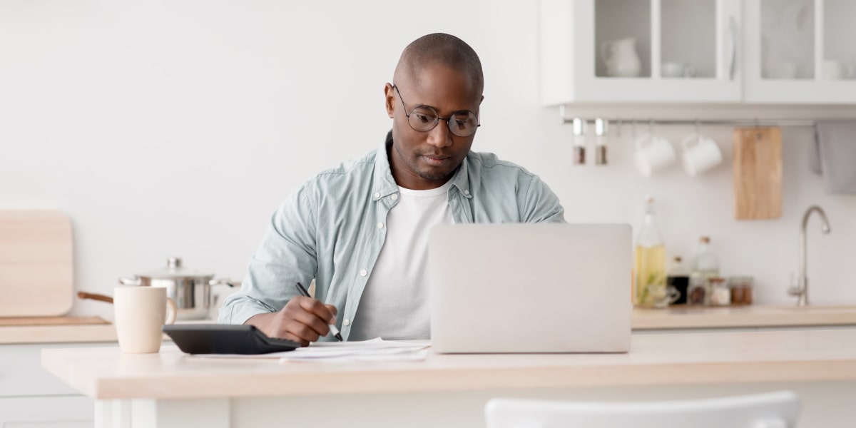 A digital marketing specialist working from a kitchen table, looking at a laptop