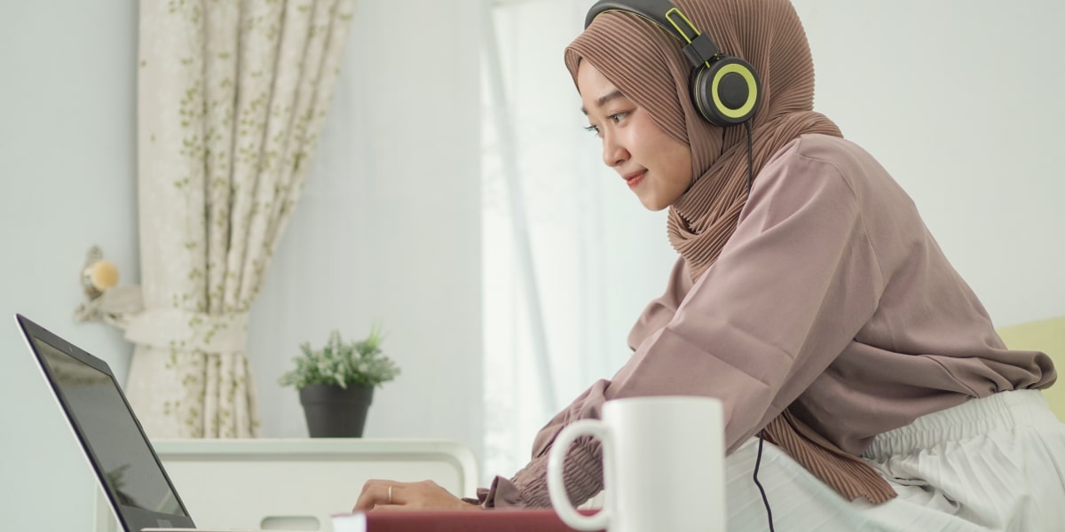 A digital marketing specialist in side profile, sitting at a desk, wearing headphones