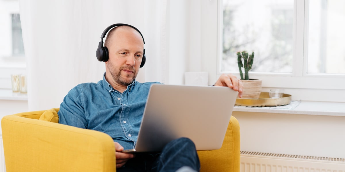 A social media specialist wearing headphones, working on a laptop