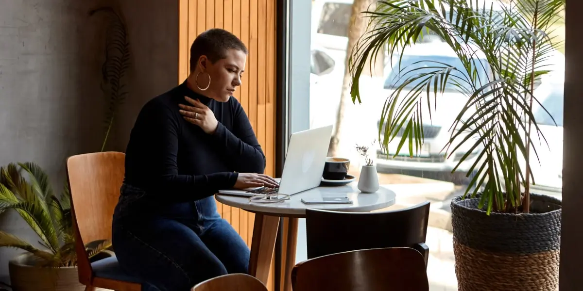 A performance marketing manager sitting at a table in a cafe, working on a laptop
