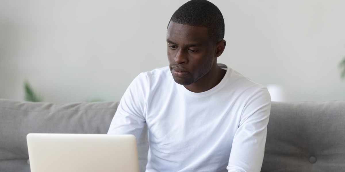 A social media specialist working on a laptop, sitting on a couch