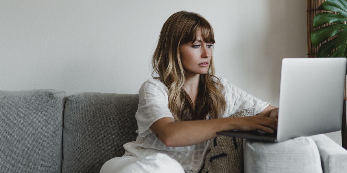 A person sitting on a sofa, shopping online using a laptop