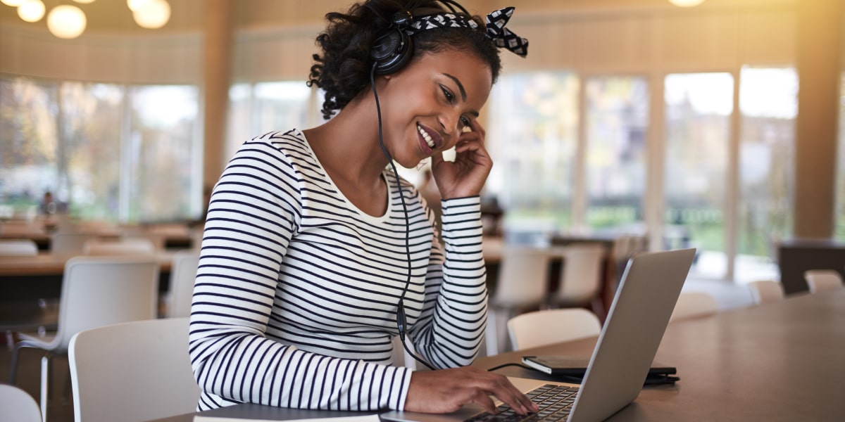 A social media manager working on a laptop, wearing headphones