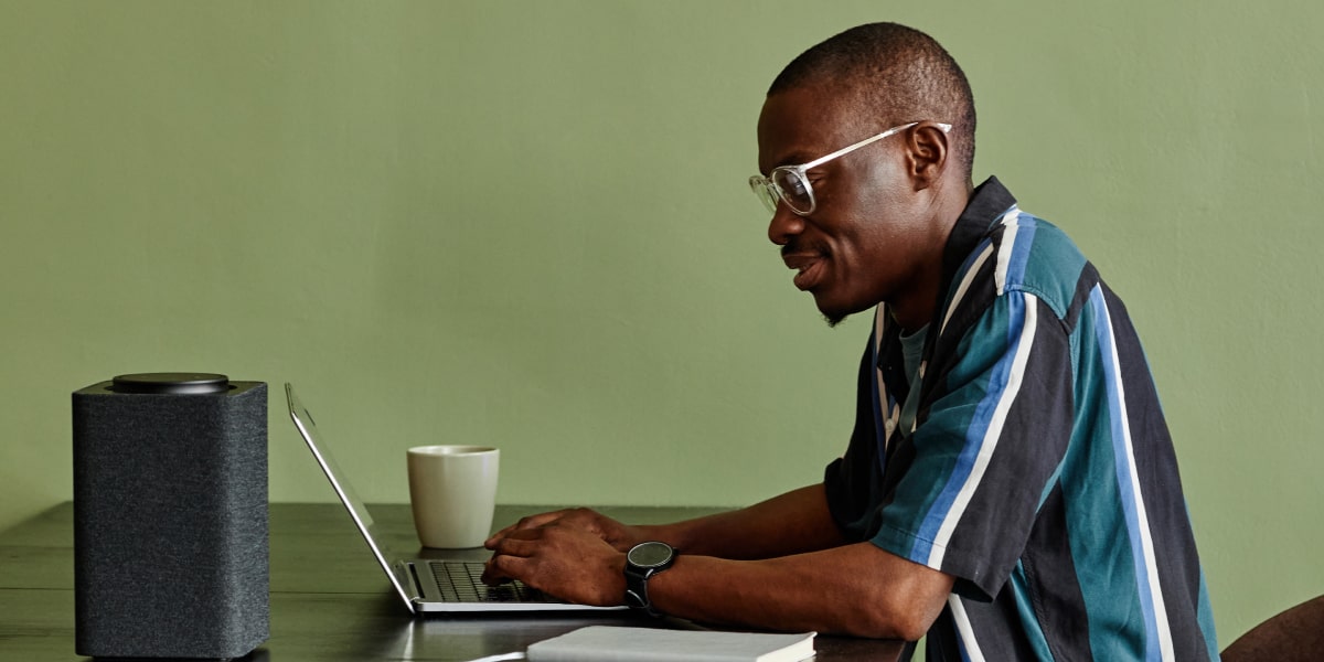 A man sits at a table with a laptop, doing a free coding class.