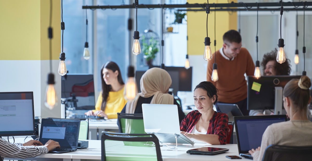 An agile team working together in a bright coworking space at their computers.