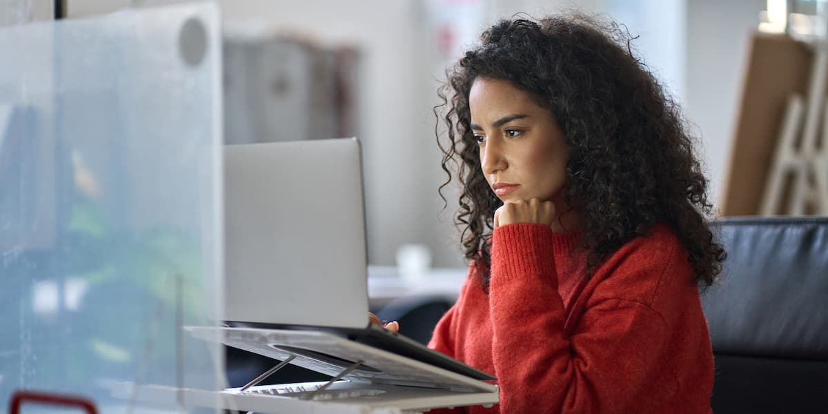 a freelance worker at her freelance job sits at a desktop computer looking at the screen