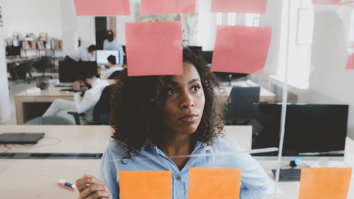 A product designer stood at a whiteboard with pen and Post-it notes