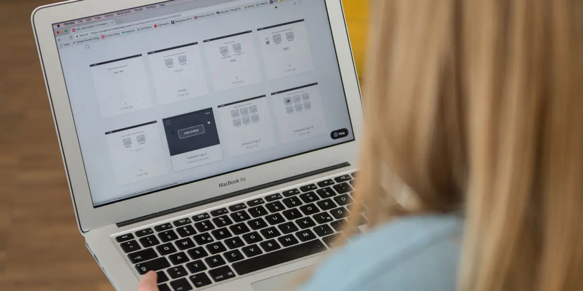 A designer uses UI design tools on a laptop