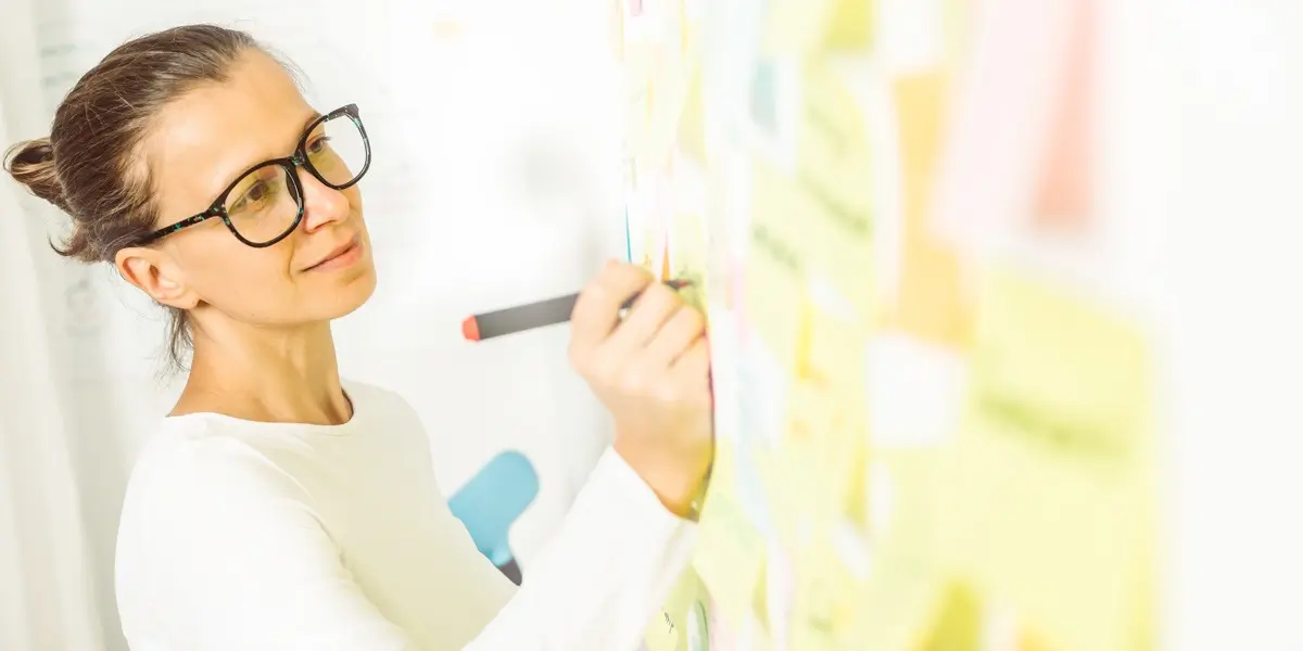 A designer writing notes on a whiteboard