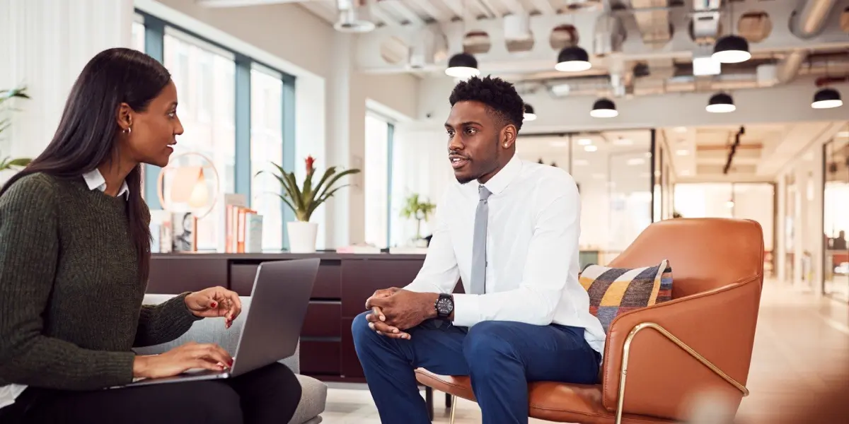 A UX researcher being interviewed by a hiring manager in a comfortable office environment