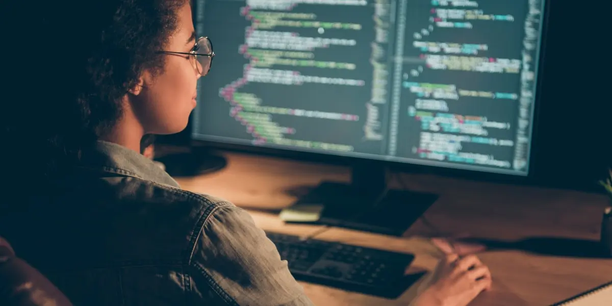 A big data engineer sitting at a desk, looking at a computer screen