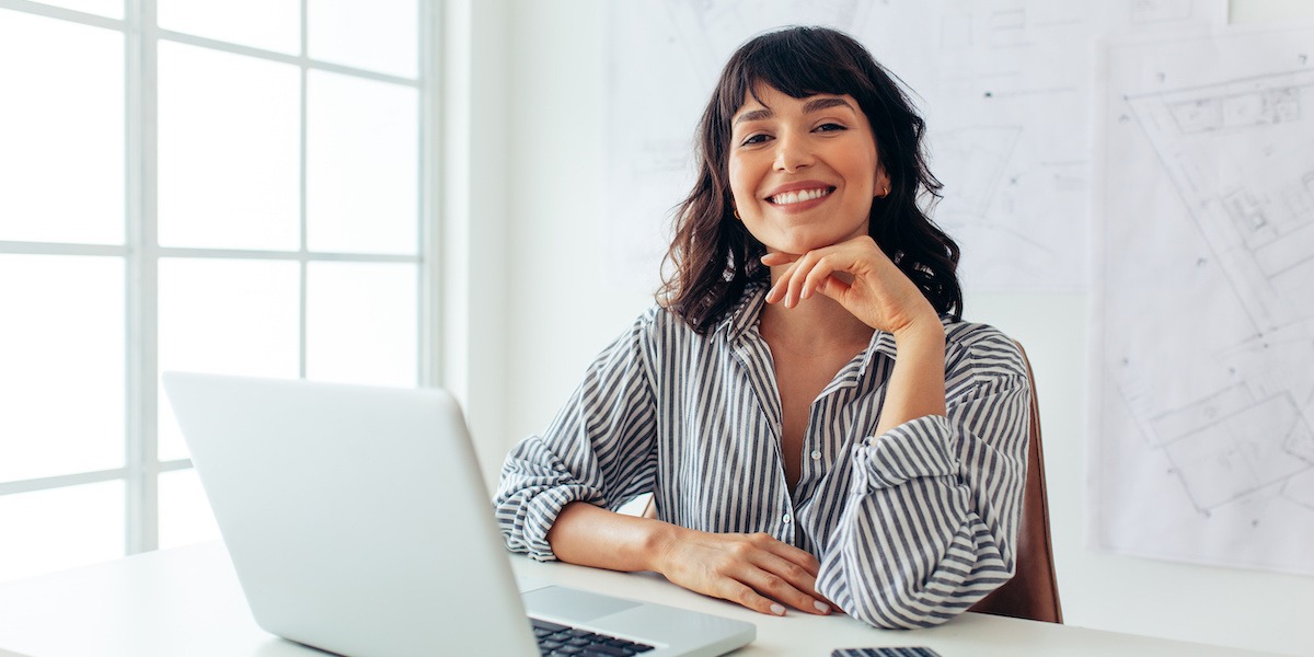 Smiling aspiring UX designer sitting at her office desk taking UX design quiz