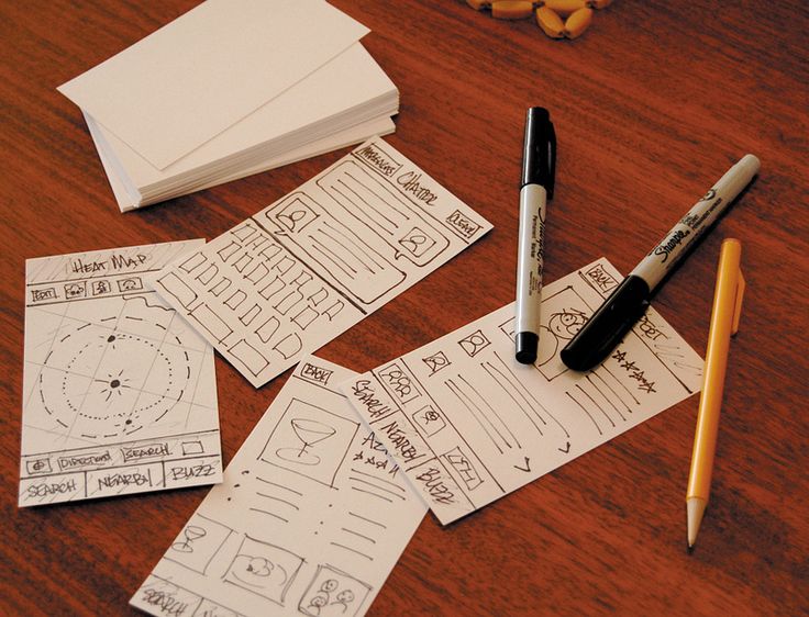 Paper wireframes scattered on a table