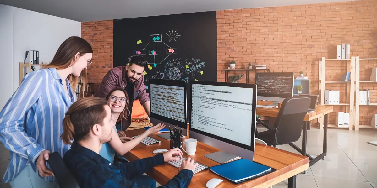 Four programmers sit in an office around a computer, studying object oriented programming.