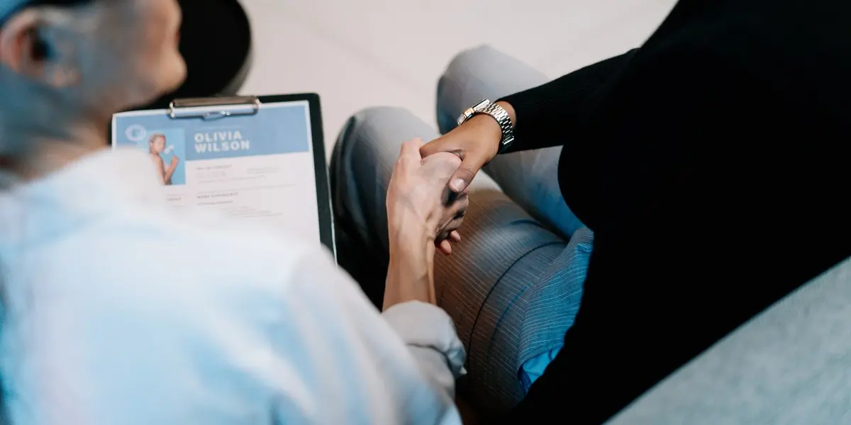 Two people sitting down shaking hands after a successful iOS developer interview