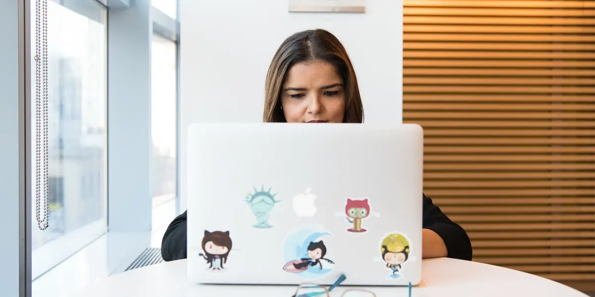 A woman sits at a laptop trying out a web development course.