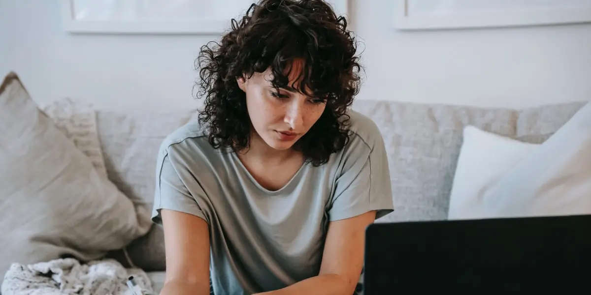 A new UX designer sitting in her living room with a laptop, considering design specializations