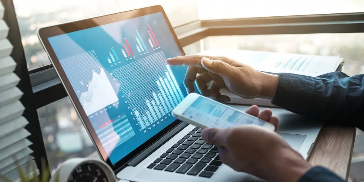 Data analyst looks at Python visualizations on a laptop and phone.
