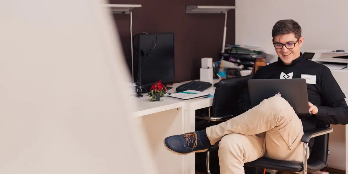 A UX design student sitting in a chair, working on a laptop