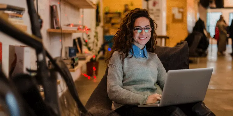 A UI designer smiling, looking at a laptop screen