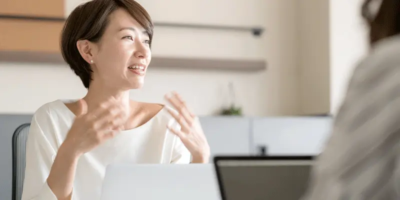 A UX designer sitting across the table from another person, explaining a concept