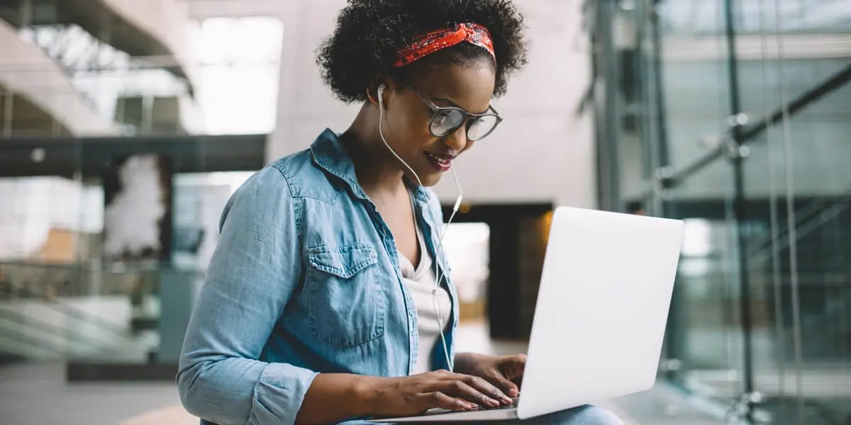 An aspiring UX designer wearing headphones and working on a laptop