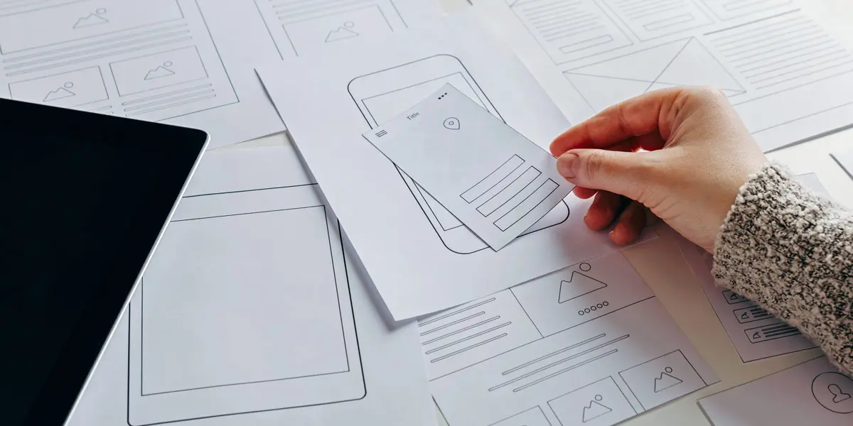 A designer's hand, rearranging parts of a paper prototype