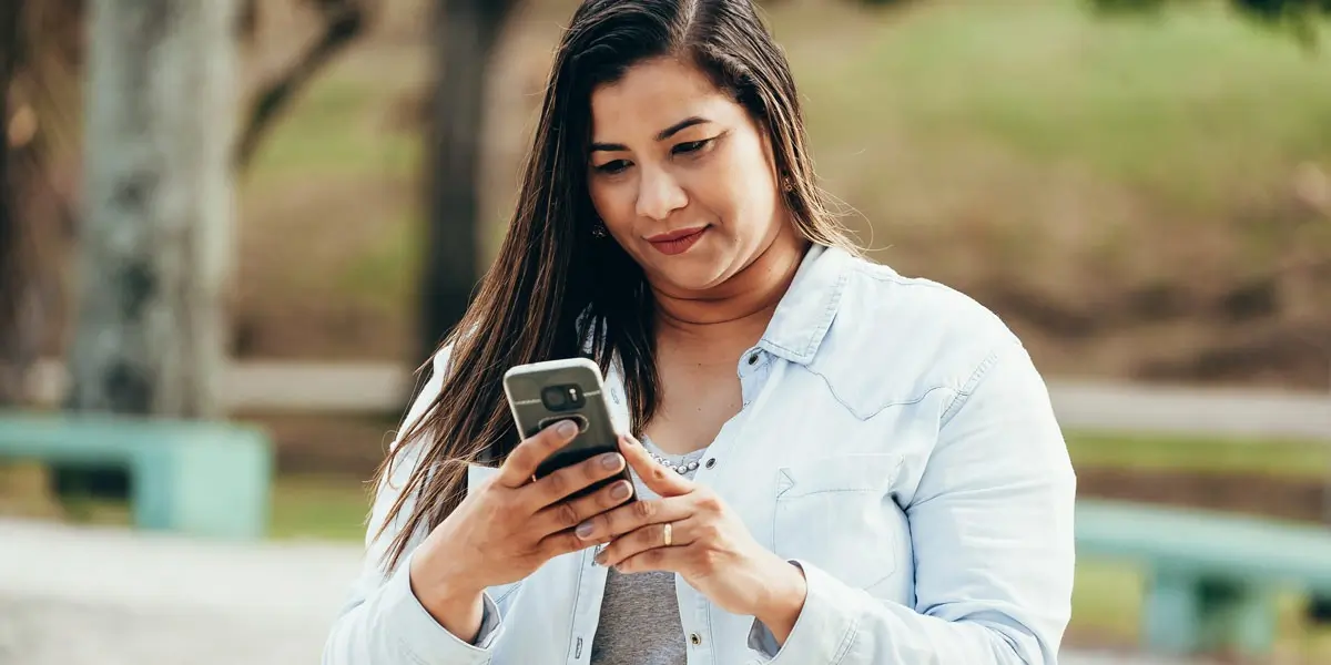 A woman in a park, walking and working on her phone