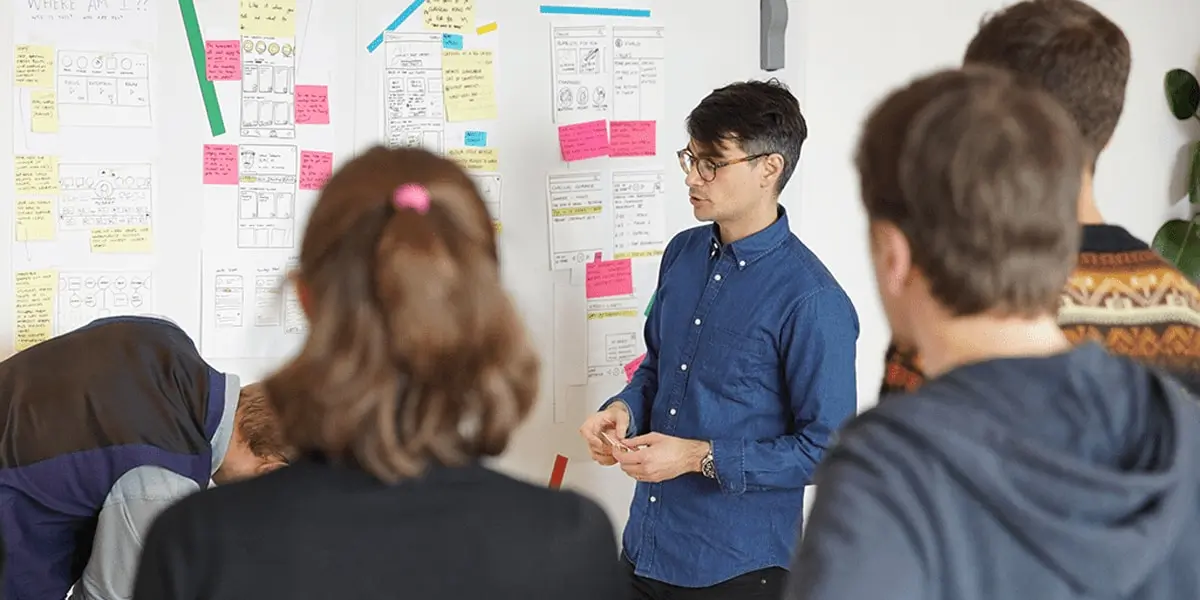 A group of designers gathered a whiteboard that's covered in notes