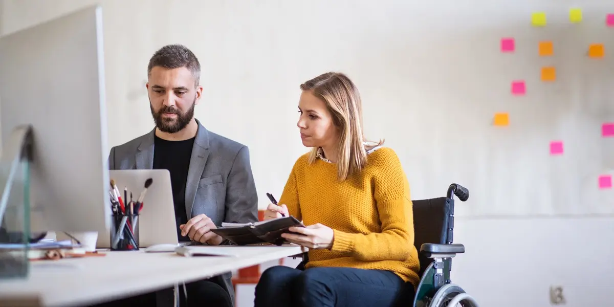 Two designers sitting at a desk in a bright office, looking at their user personas