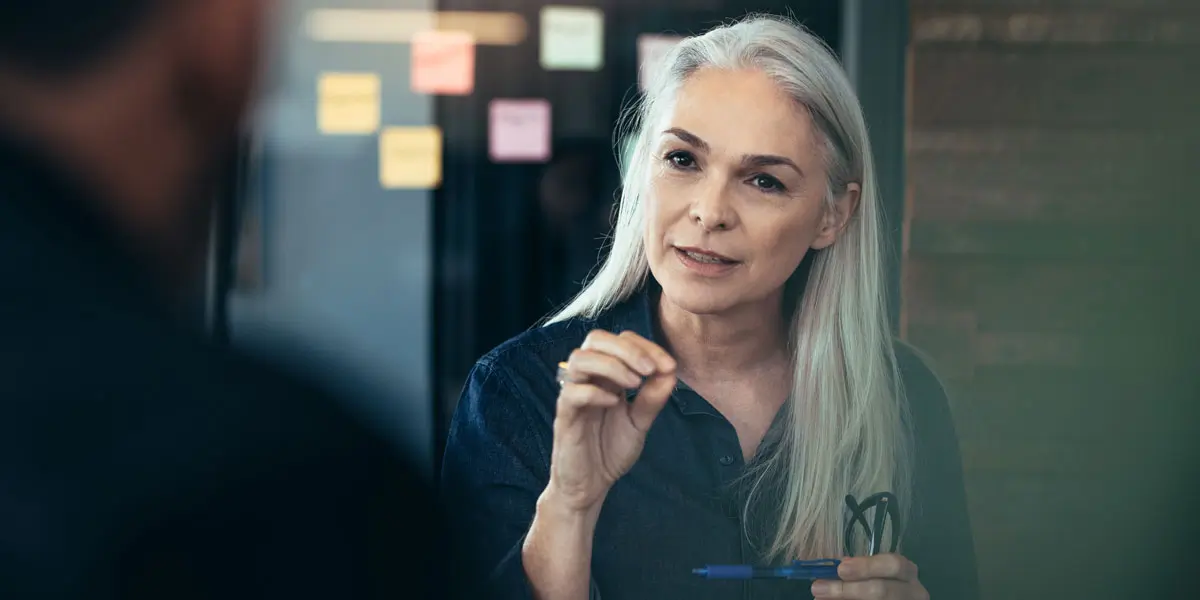 A designer sitting across the table from someone else, explaining a concept