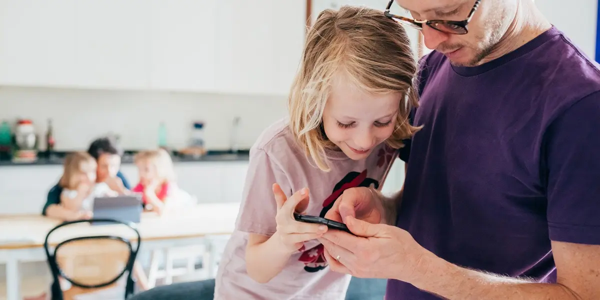 A person showing a phone screen to a child